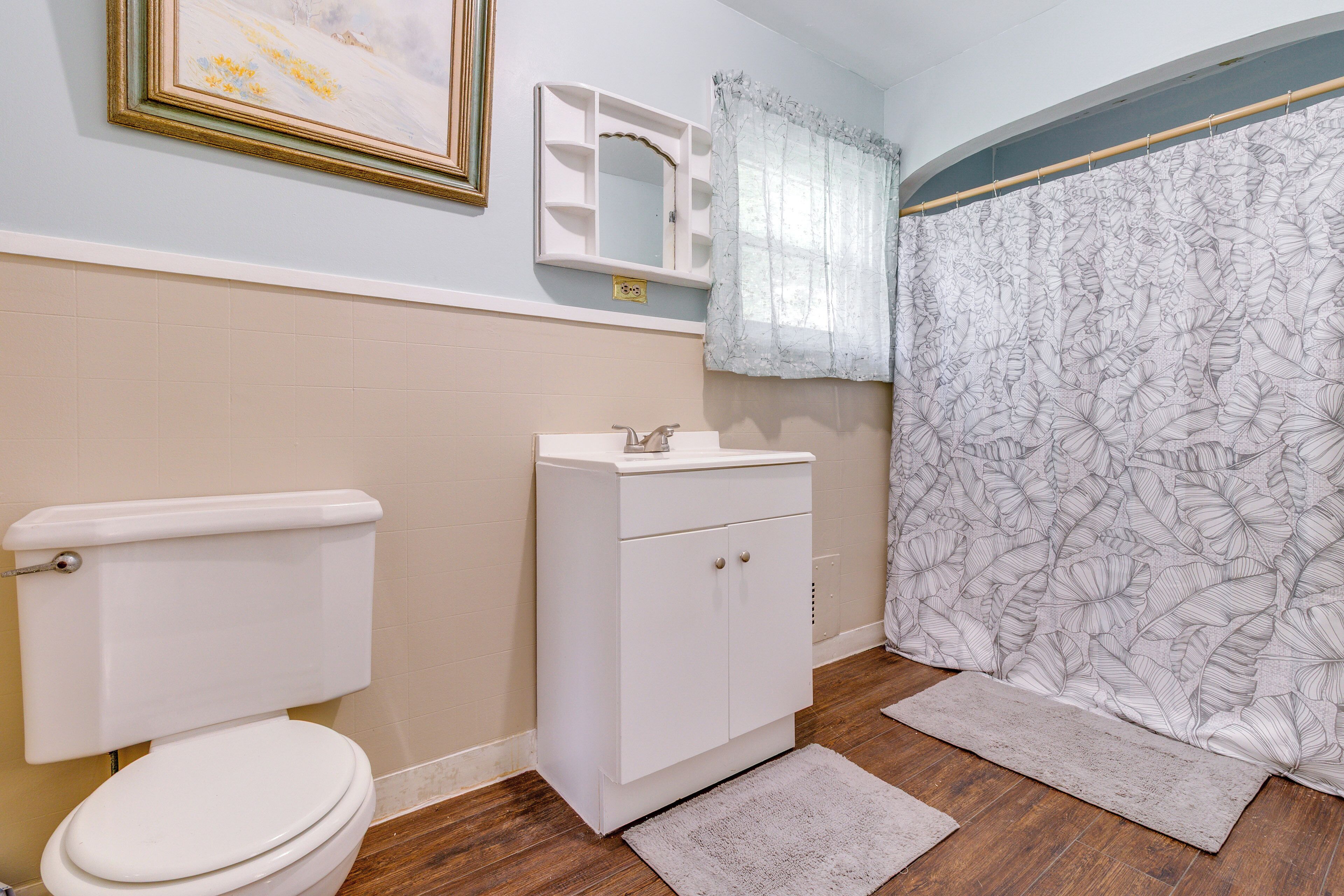 A bathroom with a toilet, a sink, a mirror, and a shower curtain.