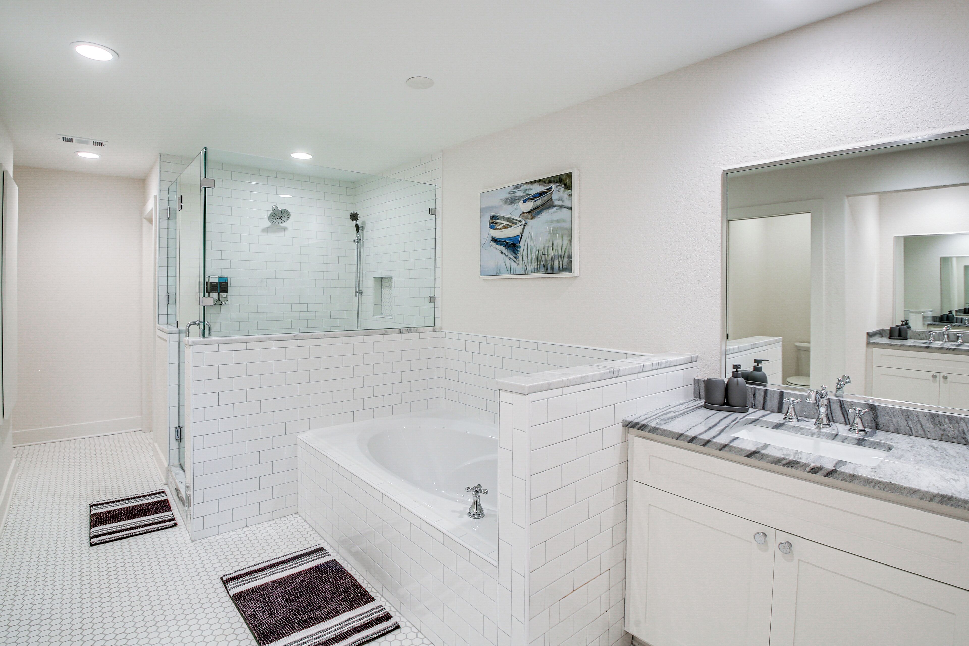 Ein modernes Badezimmer mit einer einteiligen Duschkabine, einer freistehenden Badewanne und einem Waschbecken mit Marmorplatte.