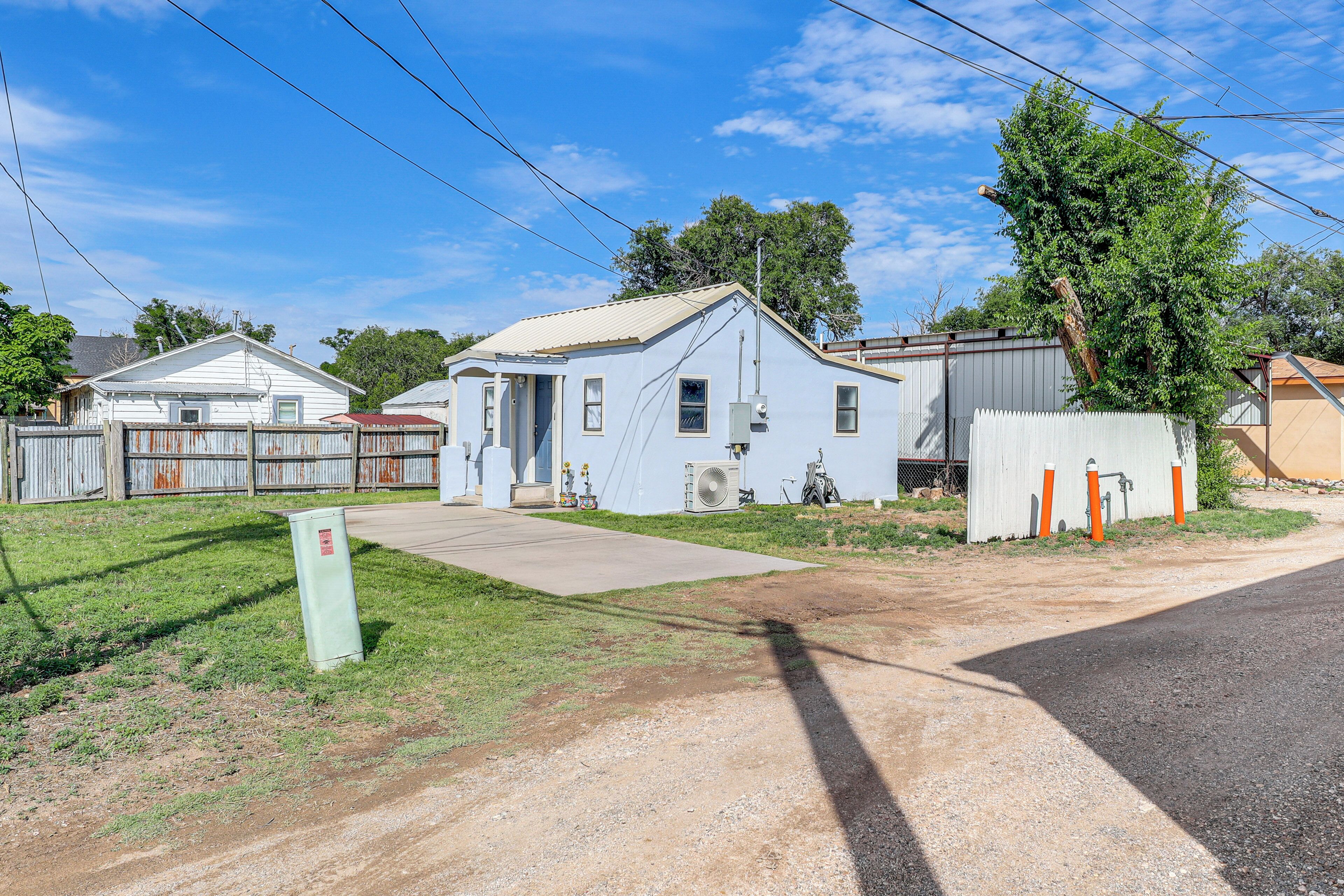 A residential area with a house, a fenced yard, and a road.
