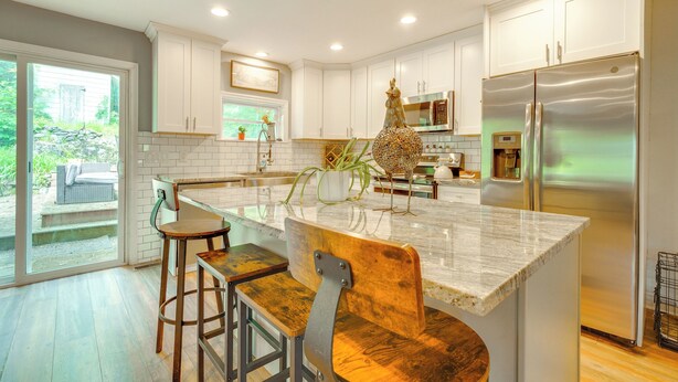 A modern kitchen with white cabinets, a stainless steel refrigerator, and a large island with bar stools. - Walk to Putnam Lake: Updated Home w/ Deck (Patterson)
