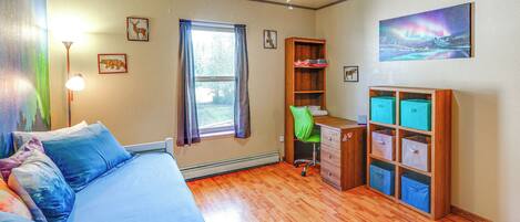 A bedroom with a bed, desk, chair, and storage units.