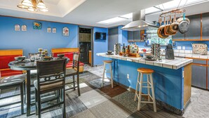 A modern kitchen with a blue accent wall, a central island with stools, and a dining area with a red bench. - Family Retreat 2 Mi to Santa's House: Pets Welcome (North Pole)