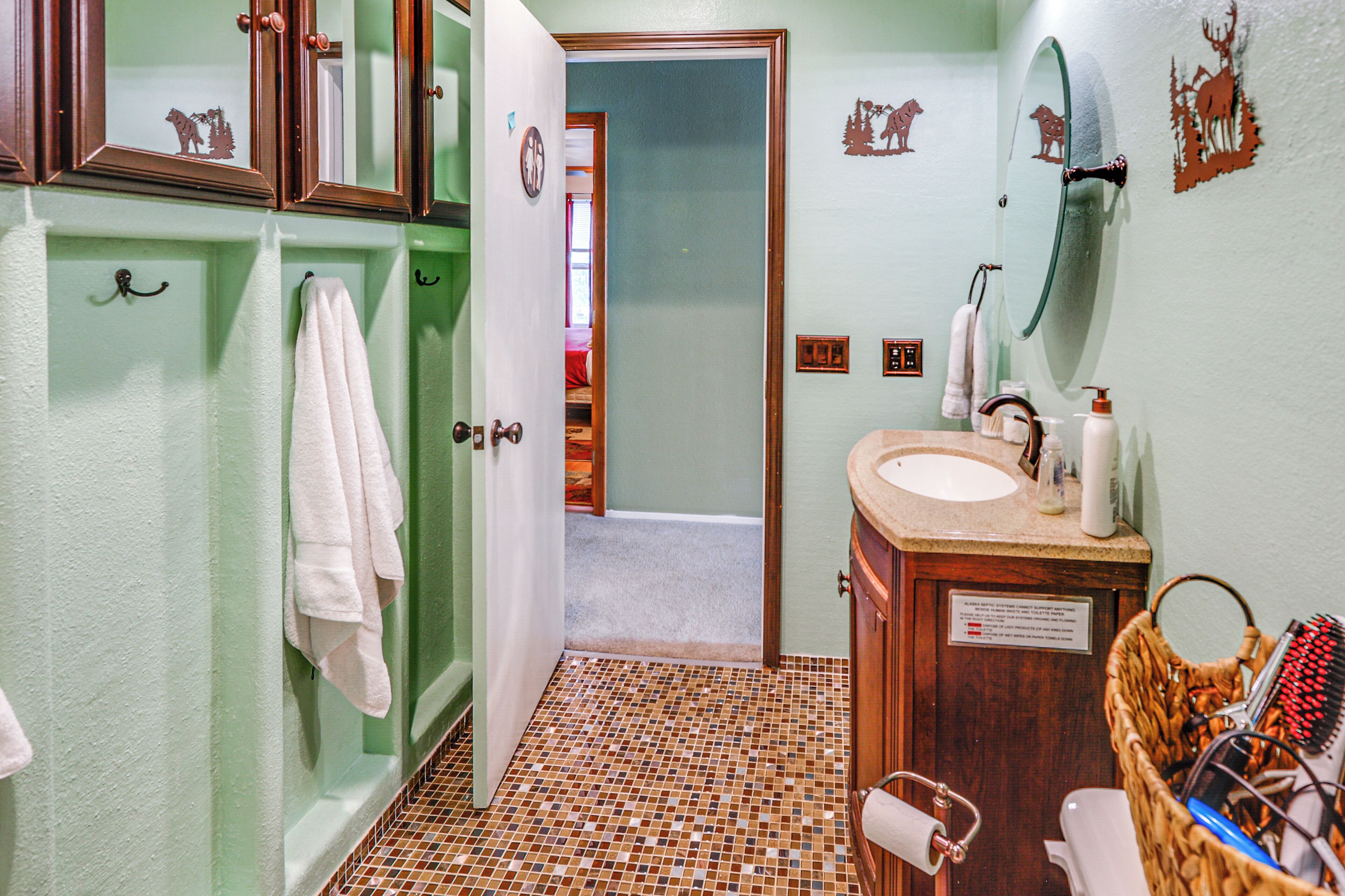 A bathroom with a tiled floor, a sink, a mirror, and a towel rack.