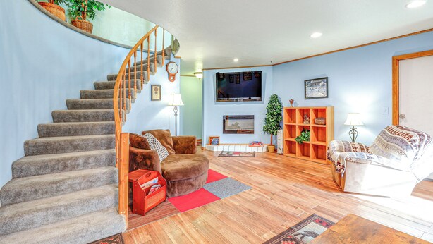 A living room with a staircase, a fireplace, a television, and a bookshelf. - Family Retreat 2 Mi to Santa's House: Pets Welcome (North Pole)