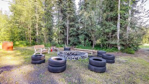 A circular seating area made of tires and a wooden bench, surrounded by trees. - Family Retreat 2 Mi to Santa's House: Pets Welcome (North Pole)