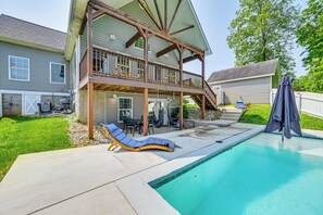 Una casa a due piani con un balcone, una piscina e mobili da esterno.