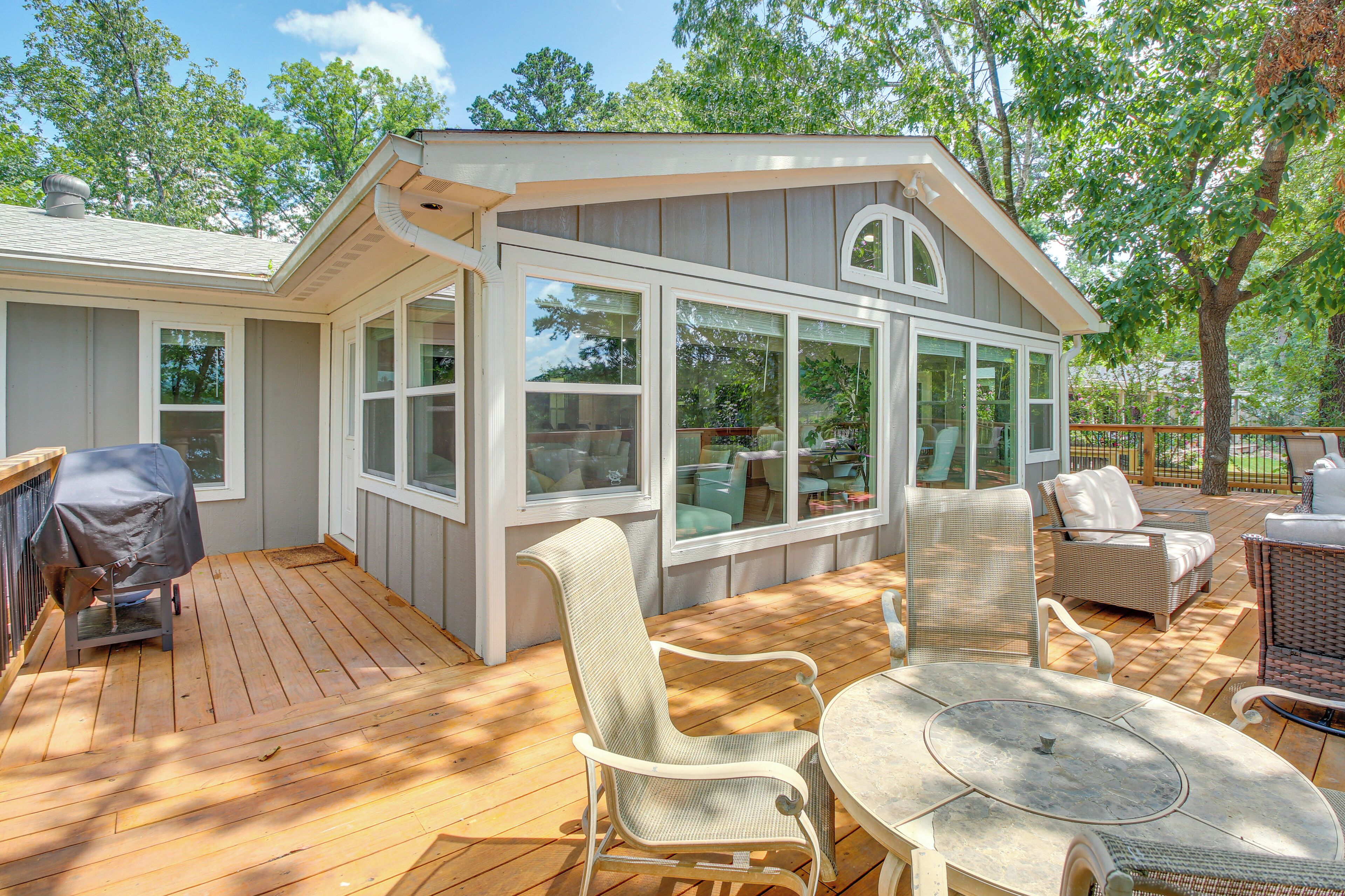 A covered outdoor deck with a dining table and chairs, a grill, and a covered seating area.