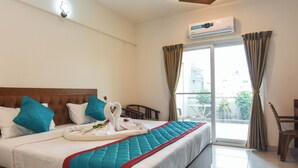 Habitación de hotel con cama, ventana con cortinas, equipo de aire acondicionado y vista a edificios.