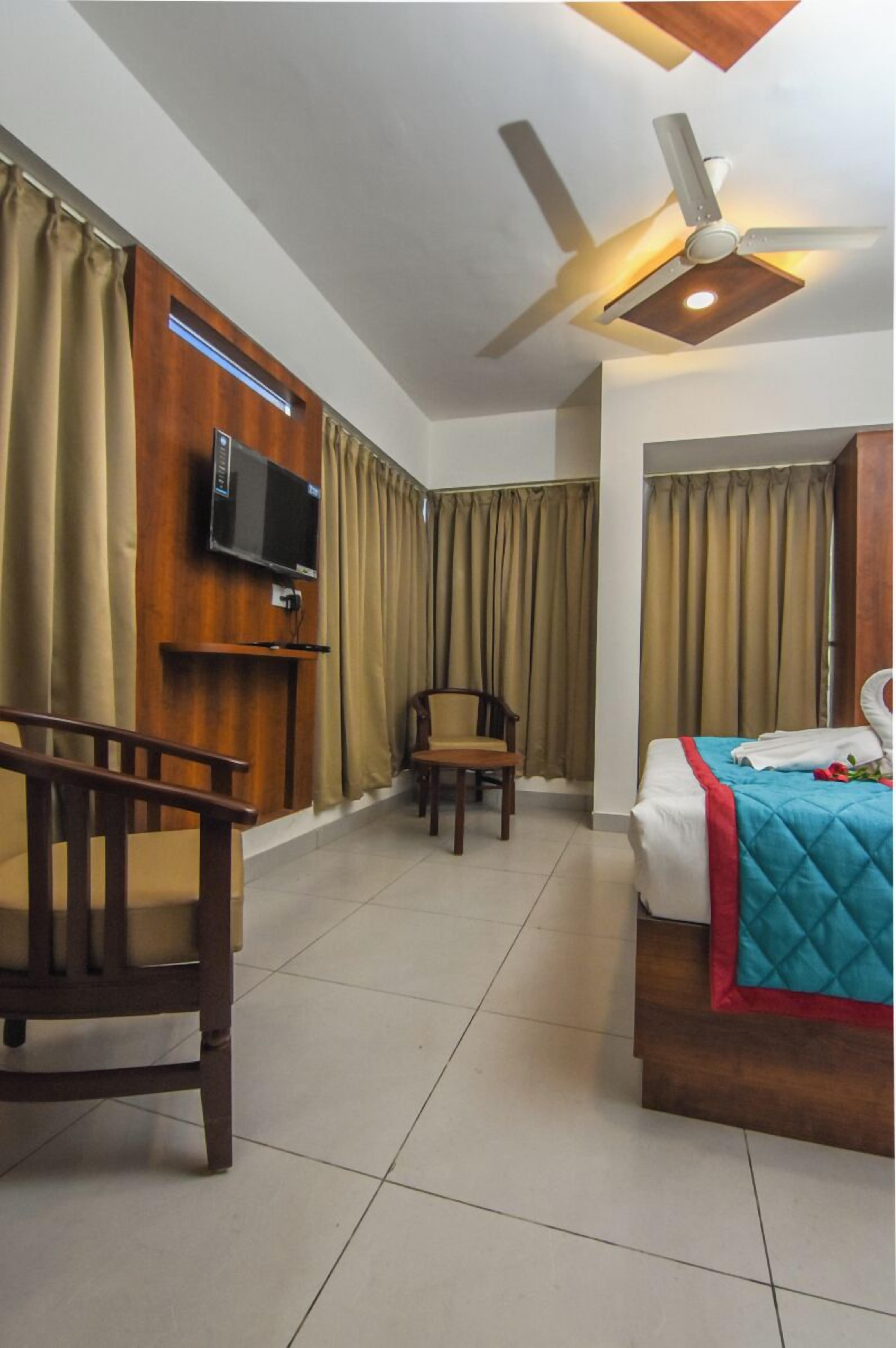 Une chambre d’hôtel équipée d’un lit, d’une chaise, d’un téléviseur fixé au mur et d’un ventilateur de plafond.