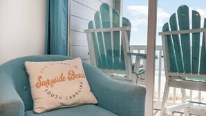 Un fauteuil de couleur turquoise avec un coussin sur lequel est inscrit : « La vie est belle à Surfside Beach, en Caroline du Sud. »