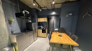 A modern kitchen with stainless steel appliances, a wooden dining table, and a small sink. - US31 Yamanote Line a famous Japanese designer apartmentdirectly to Ueno2 minutes (荒川区)