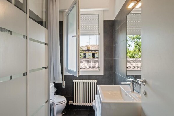 A modern bathroom with a toilet, a sink, and a window. - JOIVY Padova Porta San Giovanni (Padova)