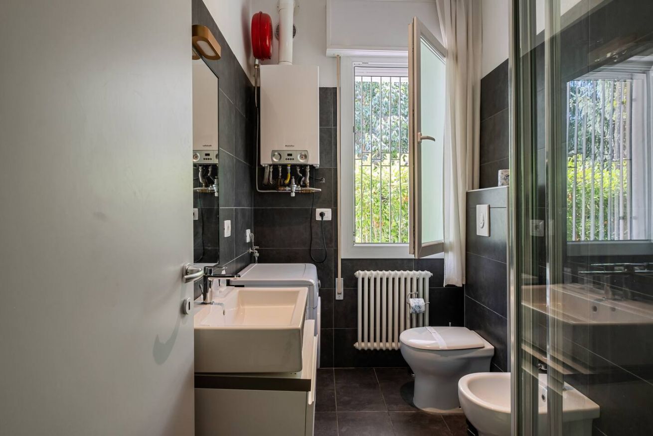 A modern bathroom with a double sink, a toilet, and a glass shower enclosure.