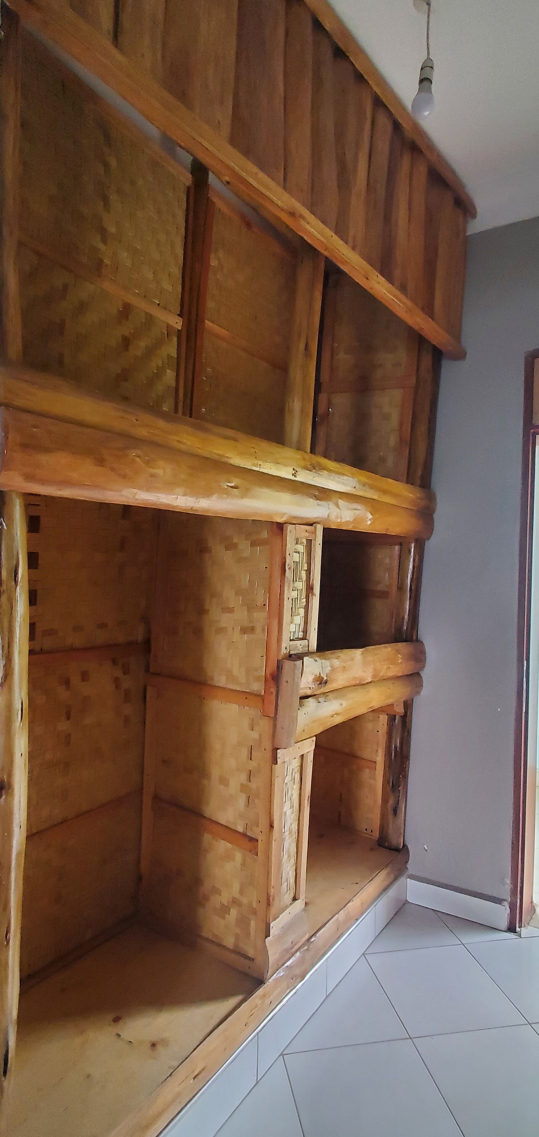Una habitación con un banco empotrado de madera, suelo de baldosas y una lámpara colgante.
