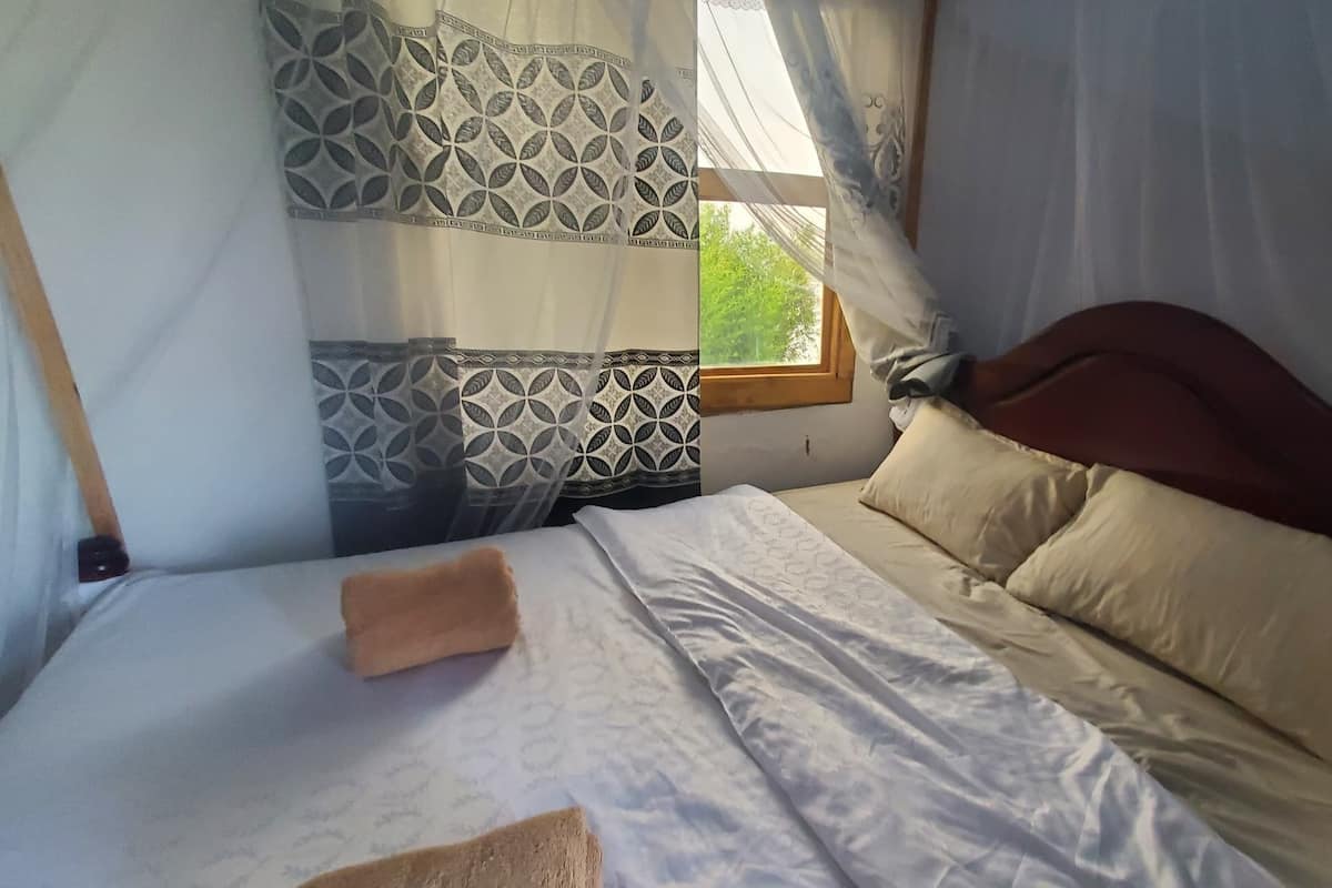 A bed with patterned bedding, a wooden headboard, and a window with a view of greenery.