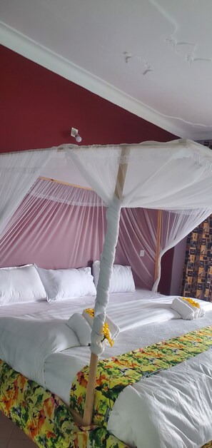 Uma cama com dossel, roupa de cama branca e edredom estampado com flores.