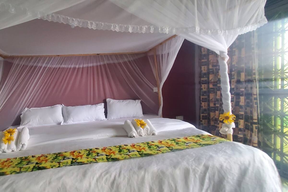 A four-poster canopy bed with white linens and a floral bedspread.