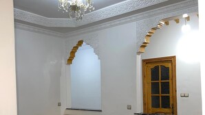 Een woonkamer met een bank, een houten kast en een kroonluchter.