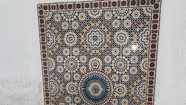 Een betegelde muur met een geometrisch patroon en een ingebouwde bank.