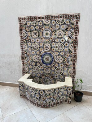 A tiled wall with a geometric pattern and a built-in bench.