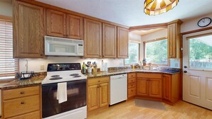 A kitchen with wooden cabinets, a white stove, a microwave, and a dishwasher.