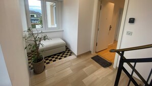 A hallway with a checkered floor, a potted plant, a bench, and a door leading to another room.