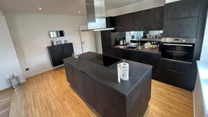 A modern kitchen with dark cabinetry, a central island, and an oven.