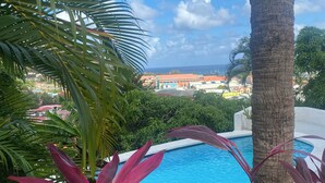 A pool surrounded by tropical plants and palm trees, with a view of colorful buildings in the background. - Fantastic villa Rodney Bay with epic views! Private pool, fab location 8 guests (Rodney Bay)