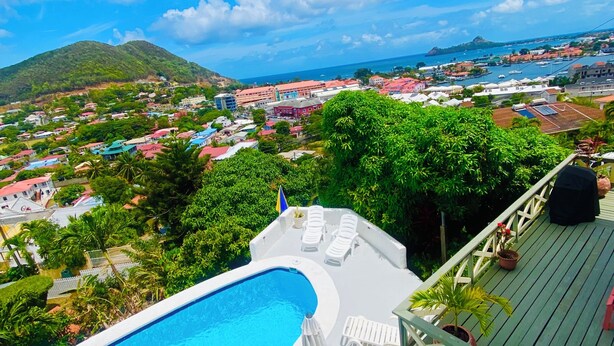 A swimming pool with lounge chairs and umbrellas, surrounded by greenery and overlooking a coastal town. - Fantastic villa Rodney Bay with epic views! Private pool, fab location 8 guests (Rodney Bay)
