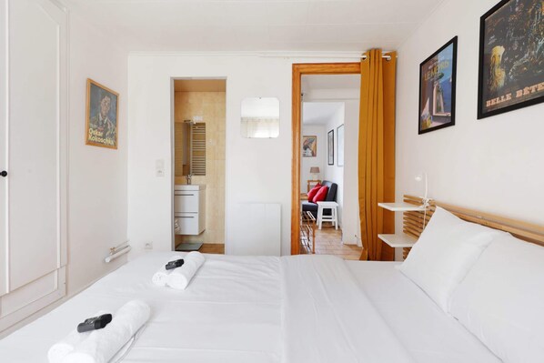 A hotel room with a bed, a desk, and a chair. There are towels on the bed and a picture on the wall.