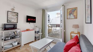 Ein modernes Wohnzimmer mit Sofa, Fernseher, Mikrowelle und Essbereich mit Tisch und Stühlen.