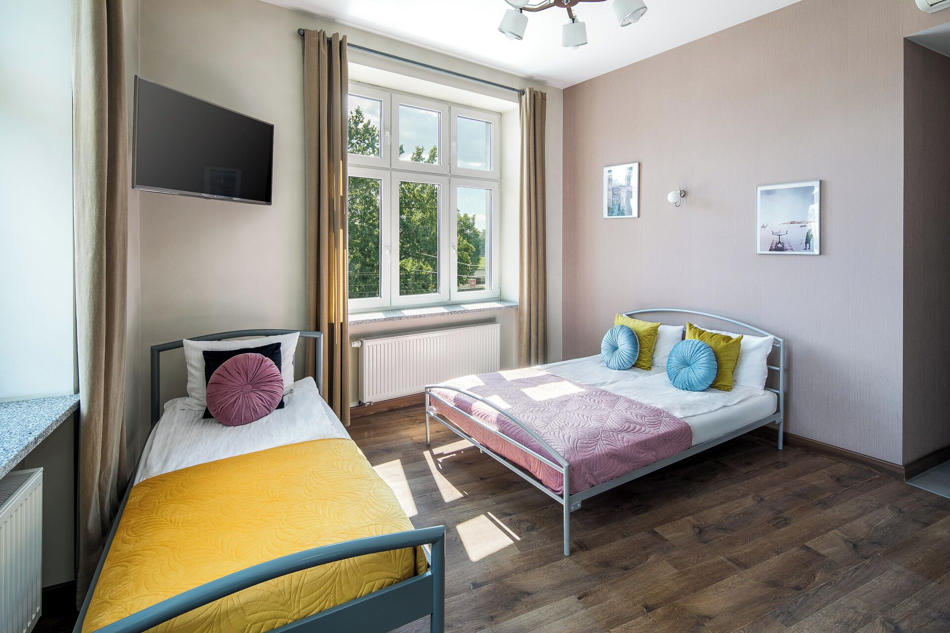 A modern bedroom with a bed, a desk, a TV, and large windows.
