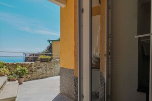 Ein Balkon mit Steinmauer, Kübelpflanzen und Blick auf das Meer.