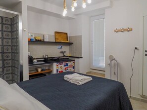 Een compacte kamer met een bed, een kitchenette en een raam.