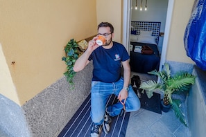 Un hombre sentado en un tapete frente a una habitación con una cama a la vista.
