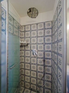 Ein Badezimmer mit Dusche, gefliesten Wänden und einer Tür.