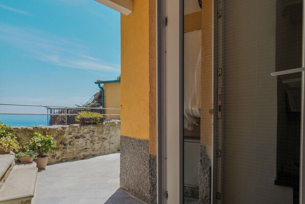 Een balkon met een stenen muur, plantenpotten en uitzicht op zee.