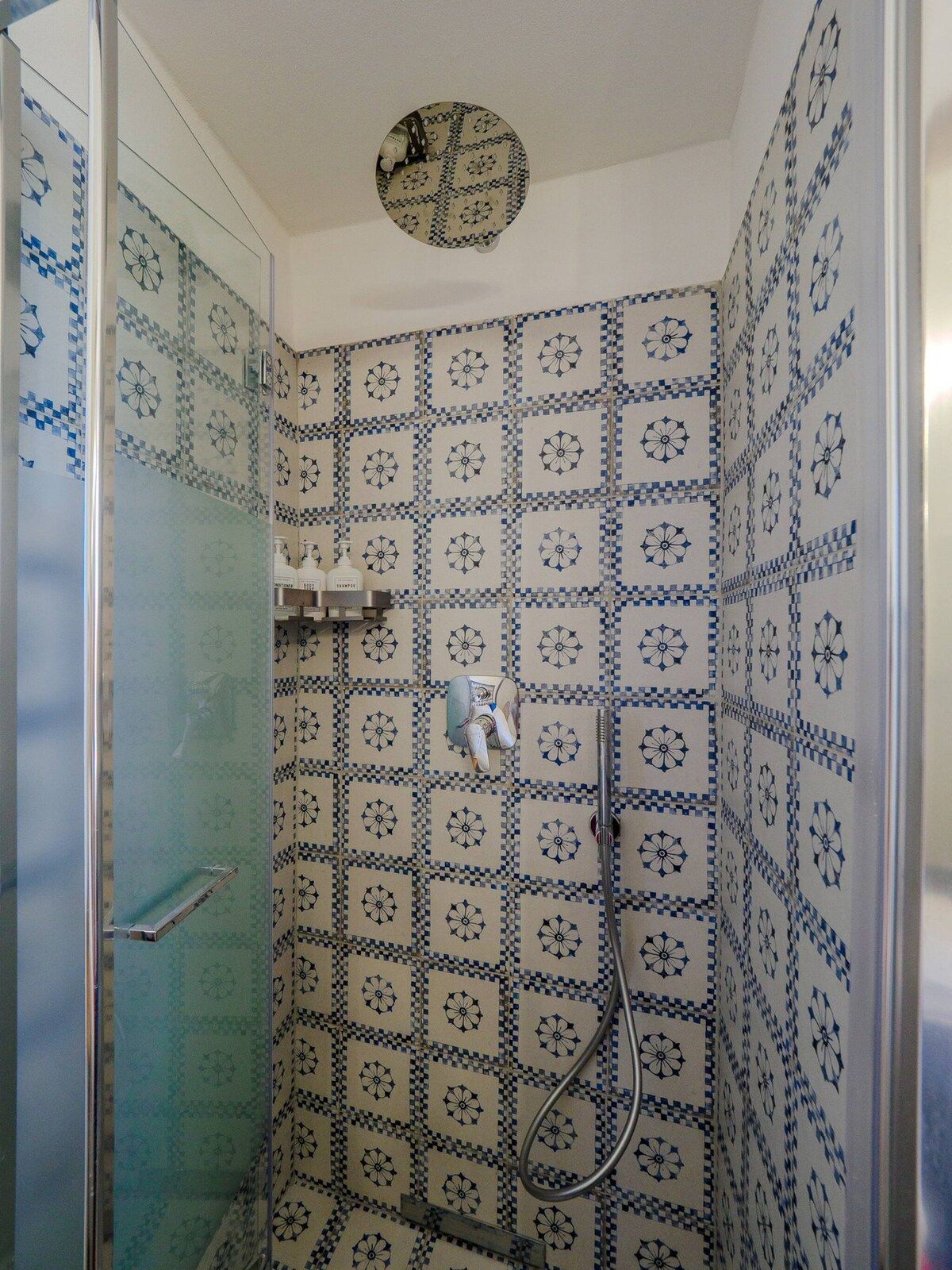 A bathroom with a shower, tiled walls, and a glass door.