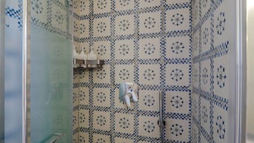 A bathroom with a shower, tiled walls, and a glass door.