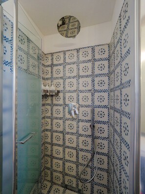 Ein Badezimmer mit Dusche, Fliesenwänden und einer Glastür.