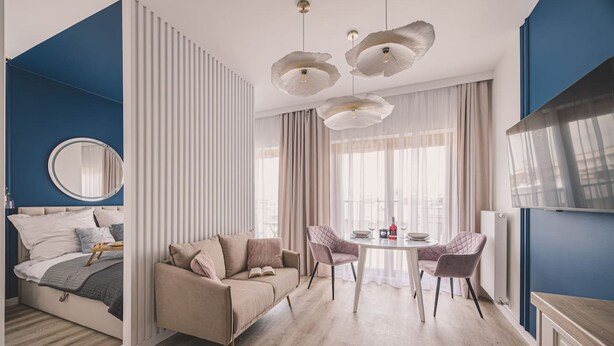 A modern bedroom with a bed, a sofa, a dining table with chairs, and a large mirror. - Rosa - Obud si w Sercu pi Knej Bydgoszczy (Bydgoszcz)