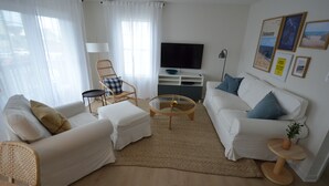A modern living room with a sofa set, a coffee table, a television, and a wall with framed pictures.
