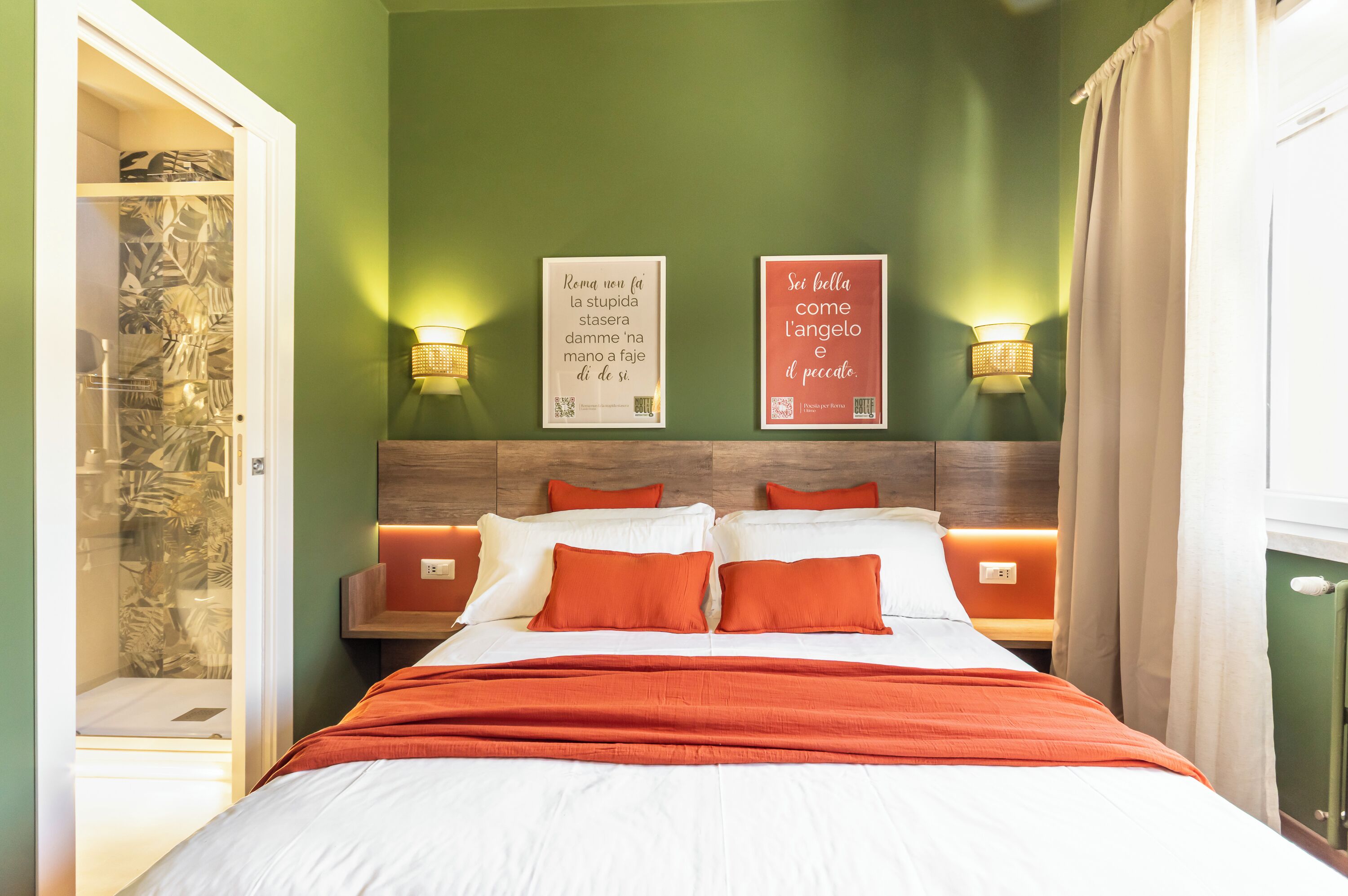 A hotel room with a bed, two wall-mounted lamps, and two framed quotes on the wall.