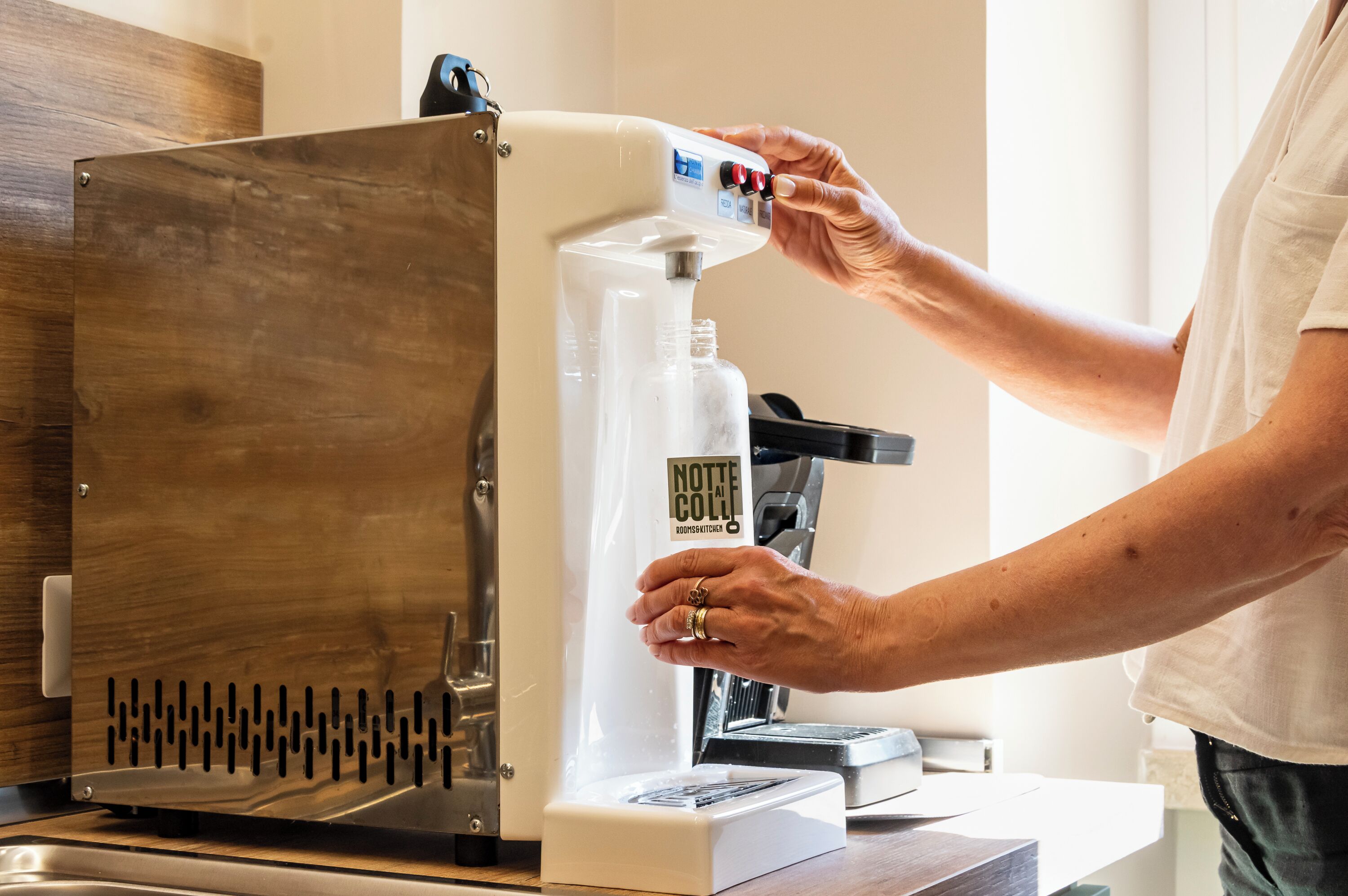 A person operating a coffee machine with a control panel and a water dispenser.