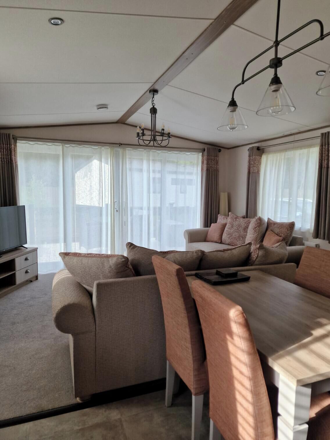 A modern living room with a sofa set, a dining table, and a TV.