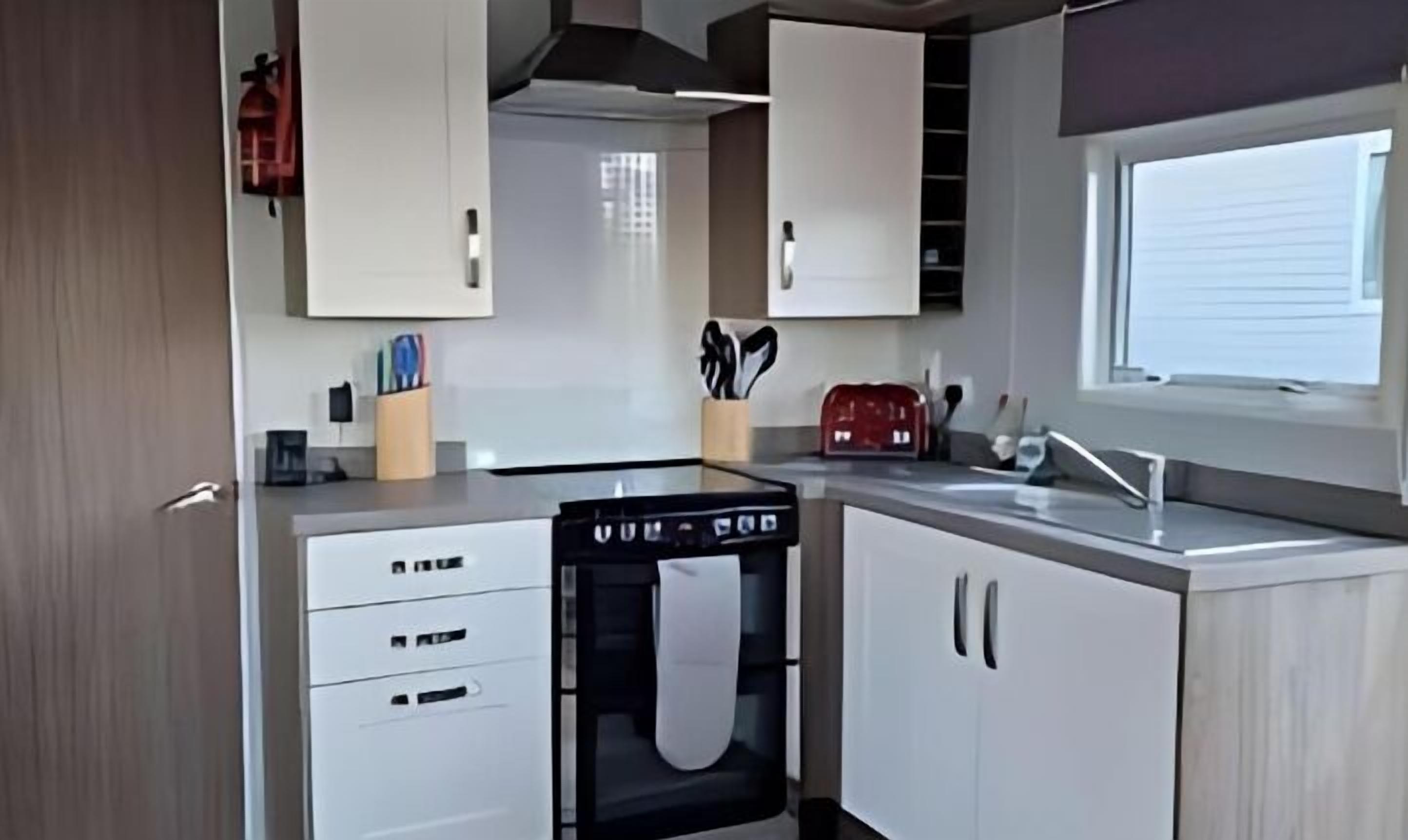 A compact kitchen with white cabinets, a built-in oven, and a window providing natural light.