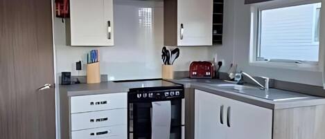 A compact kitchen with white cabinets, a built-in oven, and a window providing natural light.
