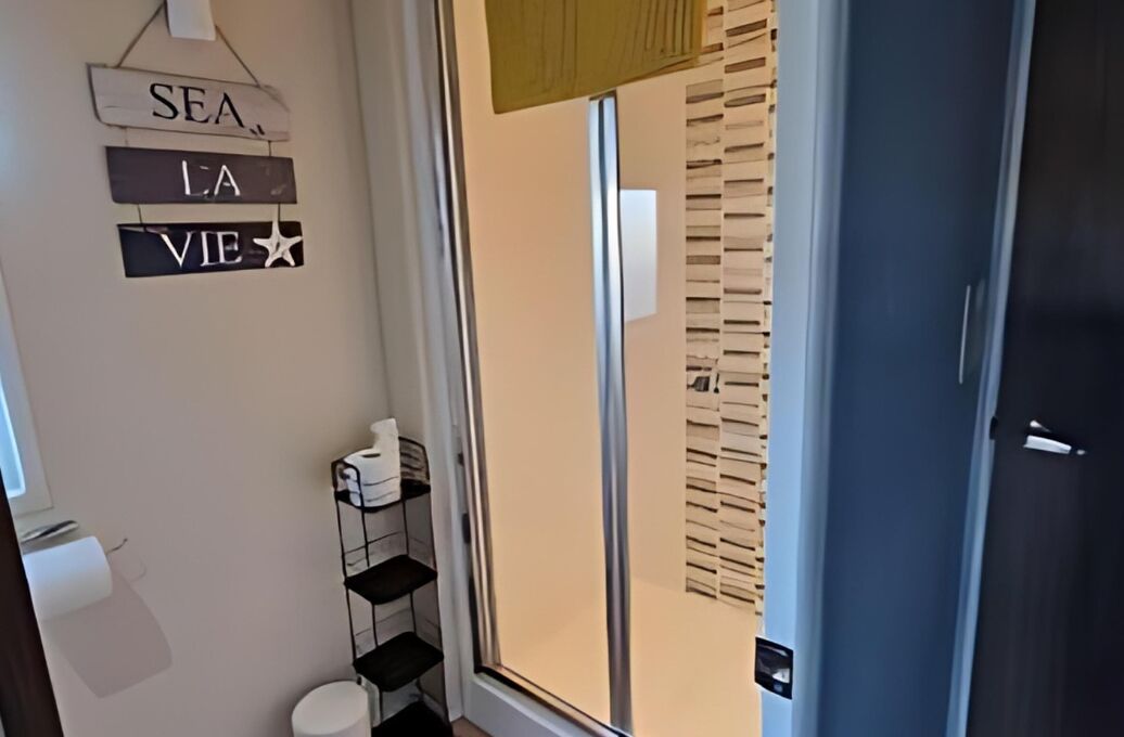Ein Badezimmer mit Toilette, Ablagefläche für Toilettenartikel und einem Schild an der Wand.