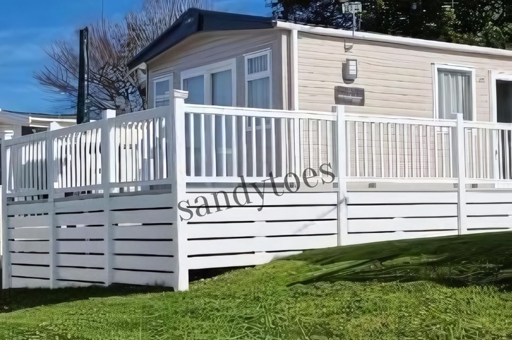 Ett enplanshus på hjul med vit fasad, en inhägnad veranda och en satellitmottagare.