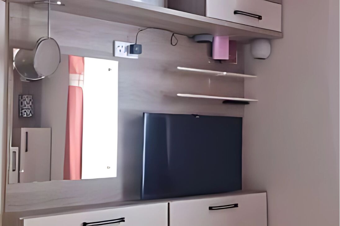 Una cocina moderna con refrigerador empotrado, gabinetes blancos y un colgador para ollas.